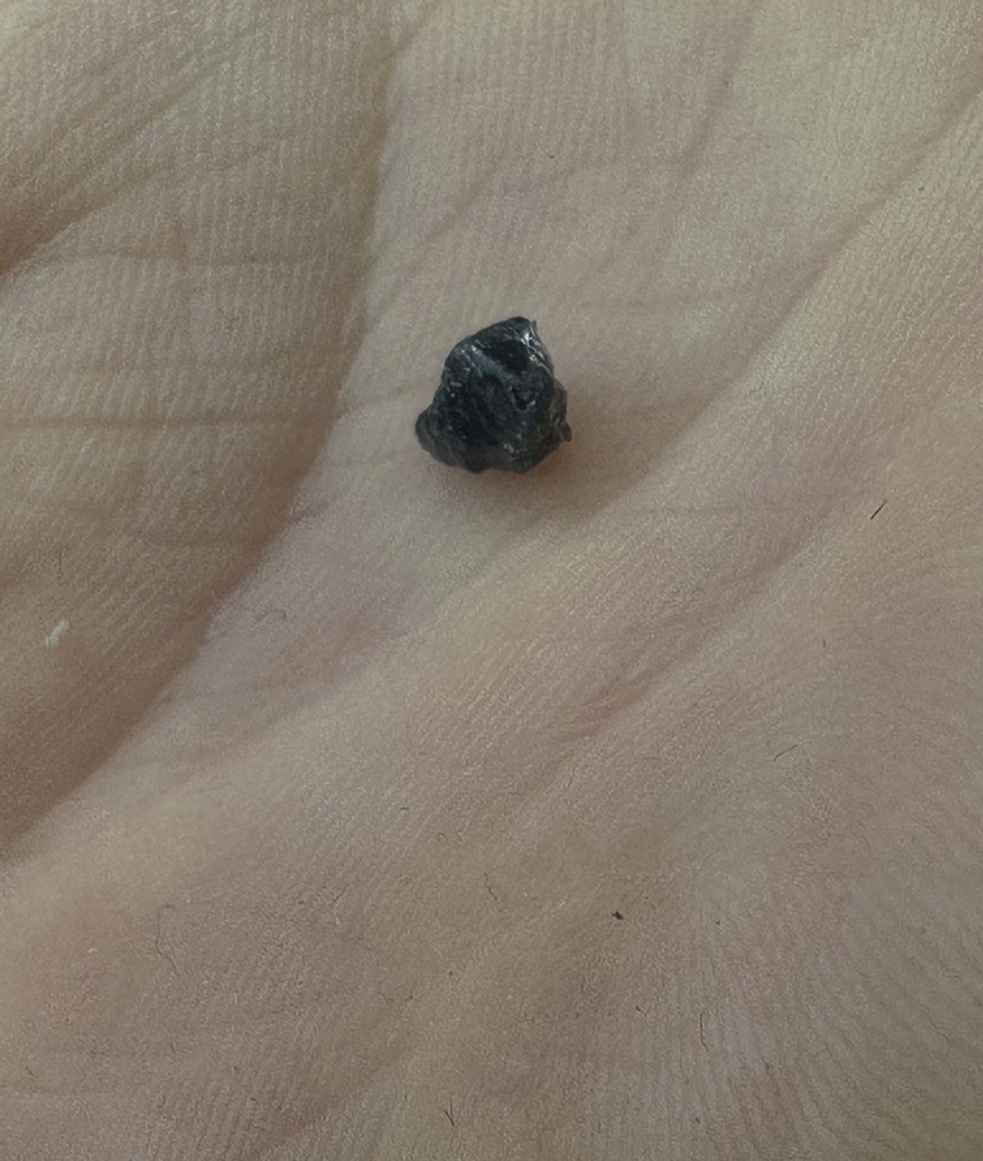 Rough gemstone found in the field, held in an open palm